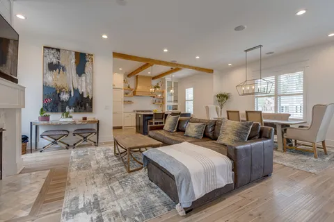 a living room with couches chairs and kitchen view with wooden floor