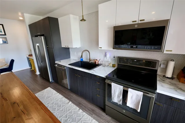 a kitchen with stainless steel appliances a stove a microwave a sink and cabinets