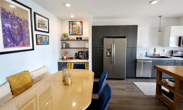 a kitchen with stainless steel appliances granite countertop a refrigerator a sink a stove and wooden floors