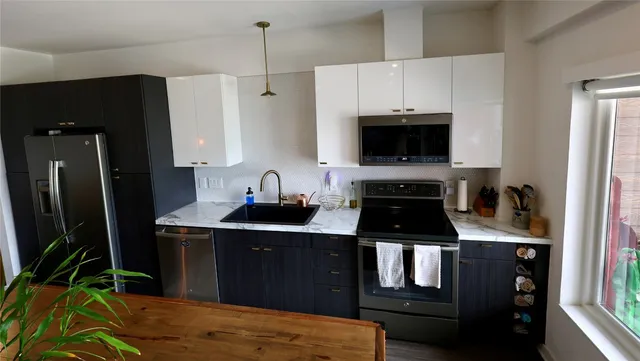 a kitchen with kitchen island granite countertop a stove top oven a sink and a refrigerator