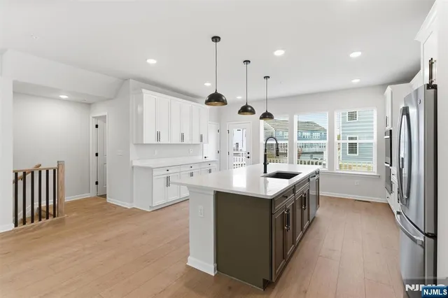 a kitchen with stainless steel appliances granite countertop a kitchen island a stove a refrigerator and a view of living room