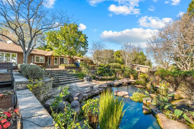an aerial view of a house with a yard and trees all around