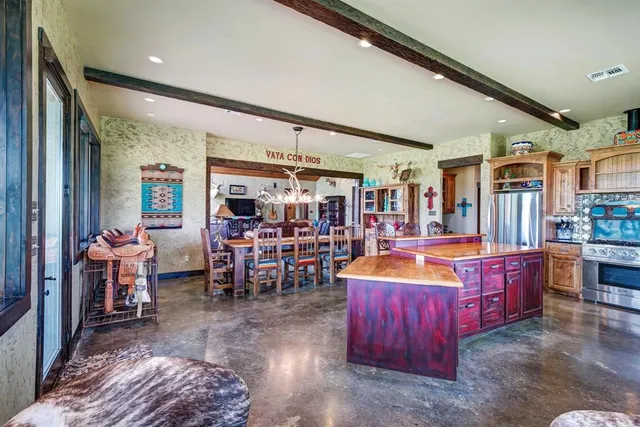 a large living room with stainless steel appliances kitchen island granite countertop a table chairs and a large window