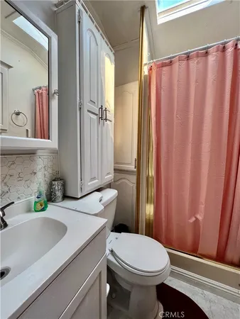 a bathroom with a sink a toilet a mirror and shower curtain