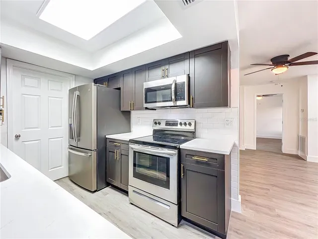 a kitchen with stainless steel appliances granite countertop a sink and a wooden floor