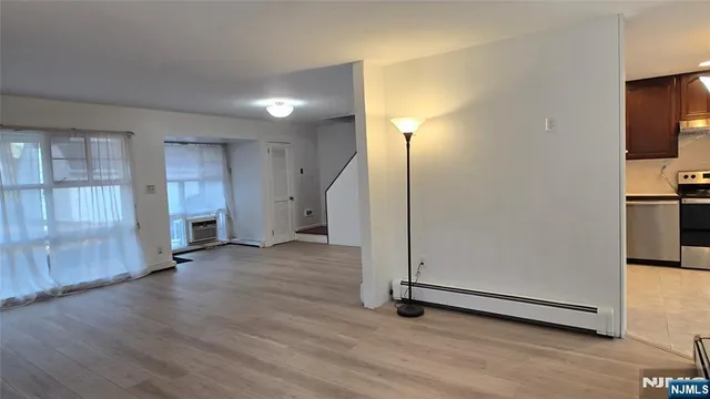 an empty room with wooden floor cabinet and windows
