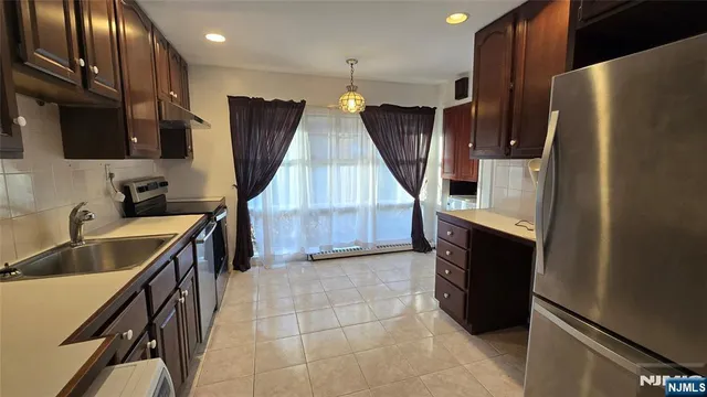 a kitchen with kitchen island granite countertop a refrigerator a sink and wooden cabinets