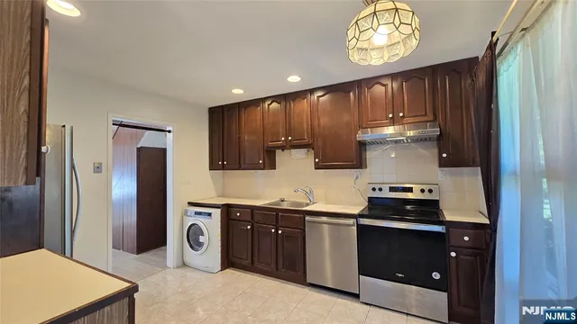 a kitchen with stainless steel appliances granite countertop a stove a refrigerator and a sink with wooden cabinets