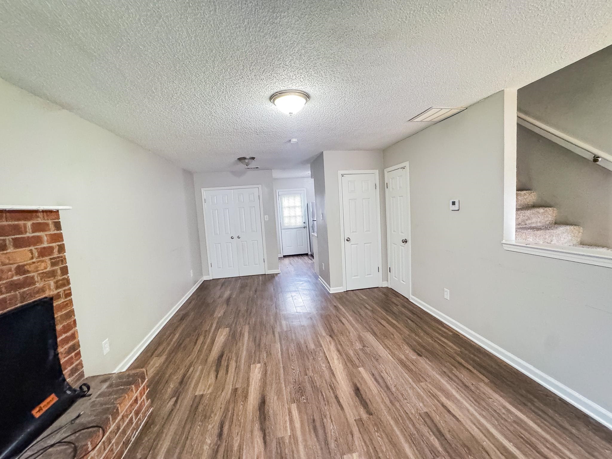 3592 Christine Road Memphis, TN 38118 - Photo 3 of 13 Spacious living area featuring wood-finish flooring, light gray walls, a brick fireplace, and white trim