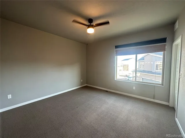 an empty room with a ceiling fan and window