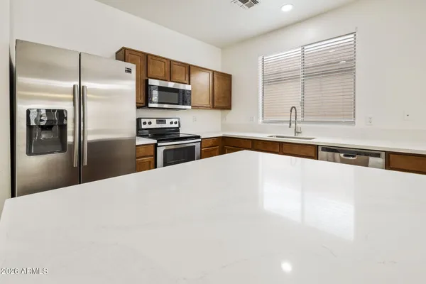 a large kitchen with stainless steel appliances a large counter top a stove a refrigerator and a sink