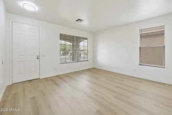 an empty room with wooden floor and windows