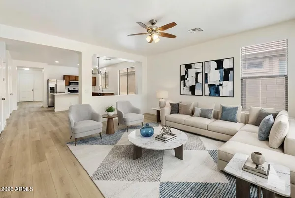 a living room with furniture a rug kitchen view and a large window