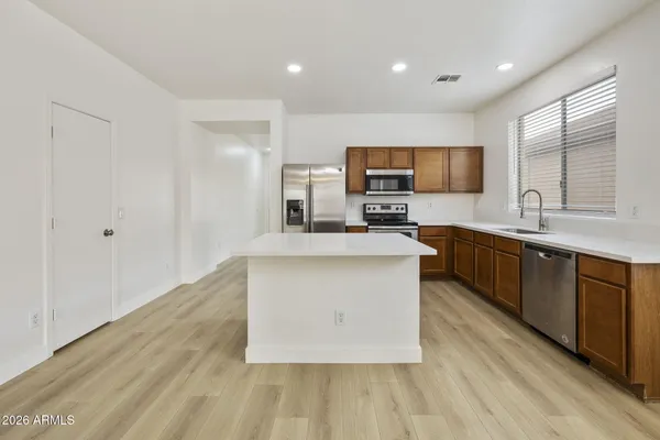 a large kitchen with stainless steel appliances a sink a stove a microwave a center island and cabinets