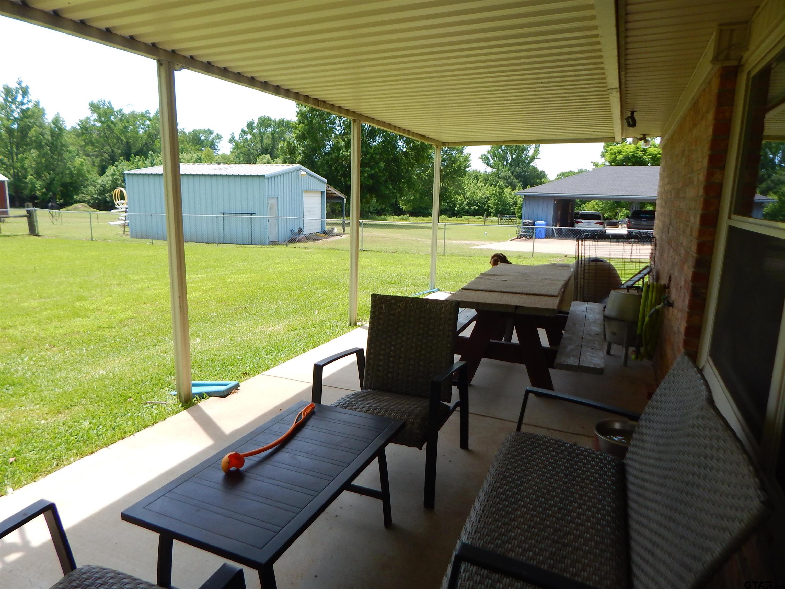3035 Arrowwood Road Gilmer, TX 75644 - Photo 24 of 32 a view of a patio with a table chairs and a backyard