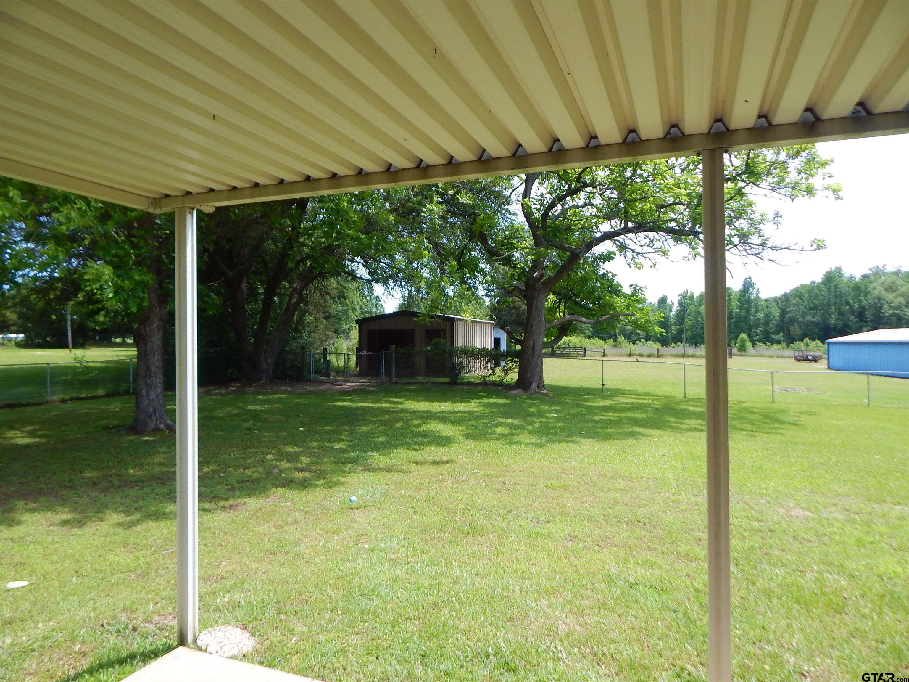3035 Arrowwood Road Gilmer, TX 75644 - Photo 26 of 32 a backyard of a house with a garden and deck