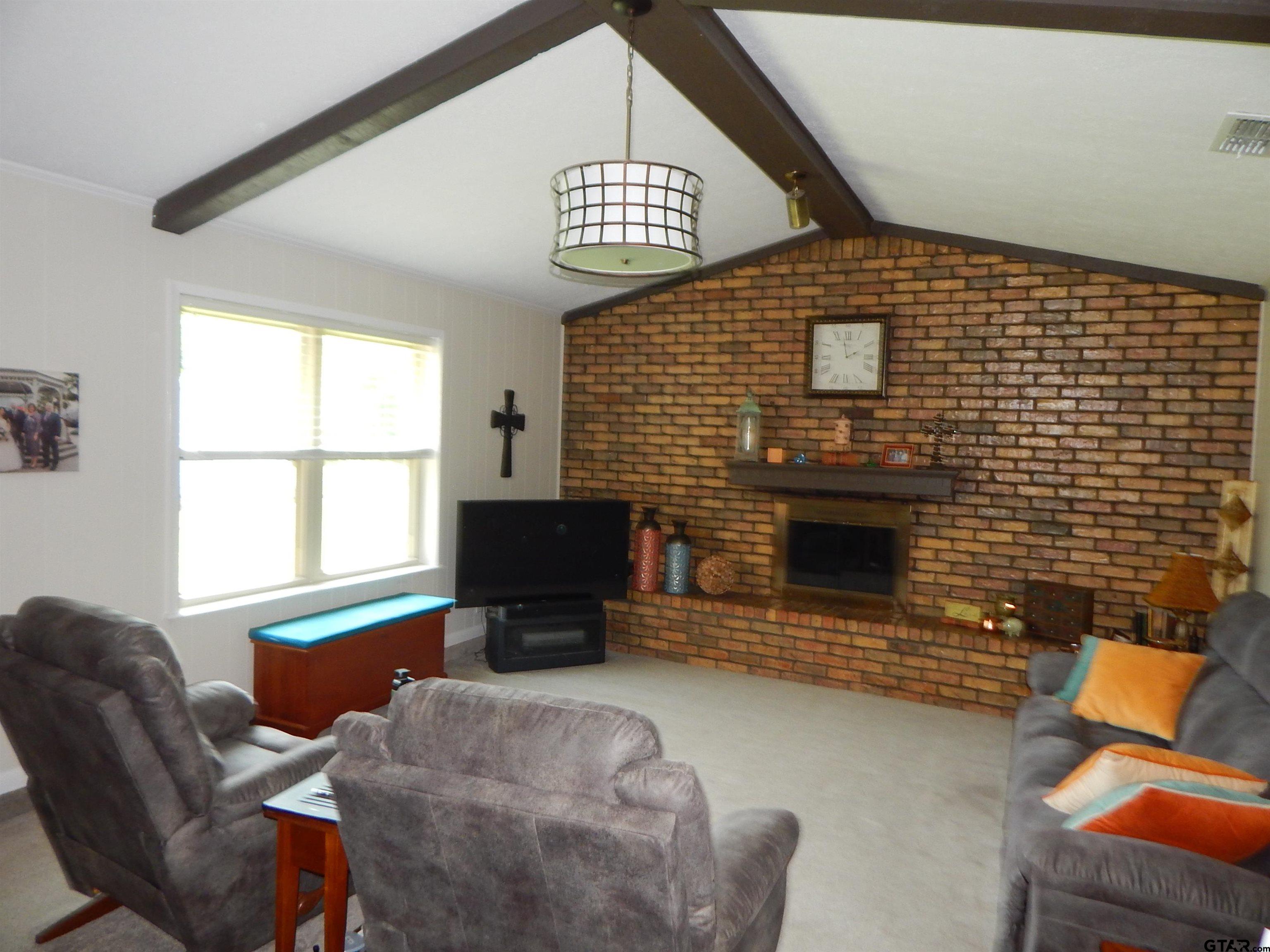 3035 Arrowwood Road Gilmer, TX 75644 - Photo 6 of 32 a living room with furniture a fireplace and a flat screen tv