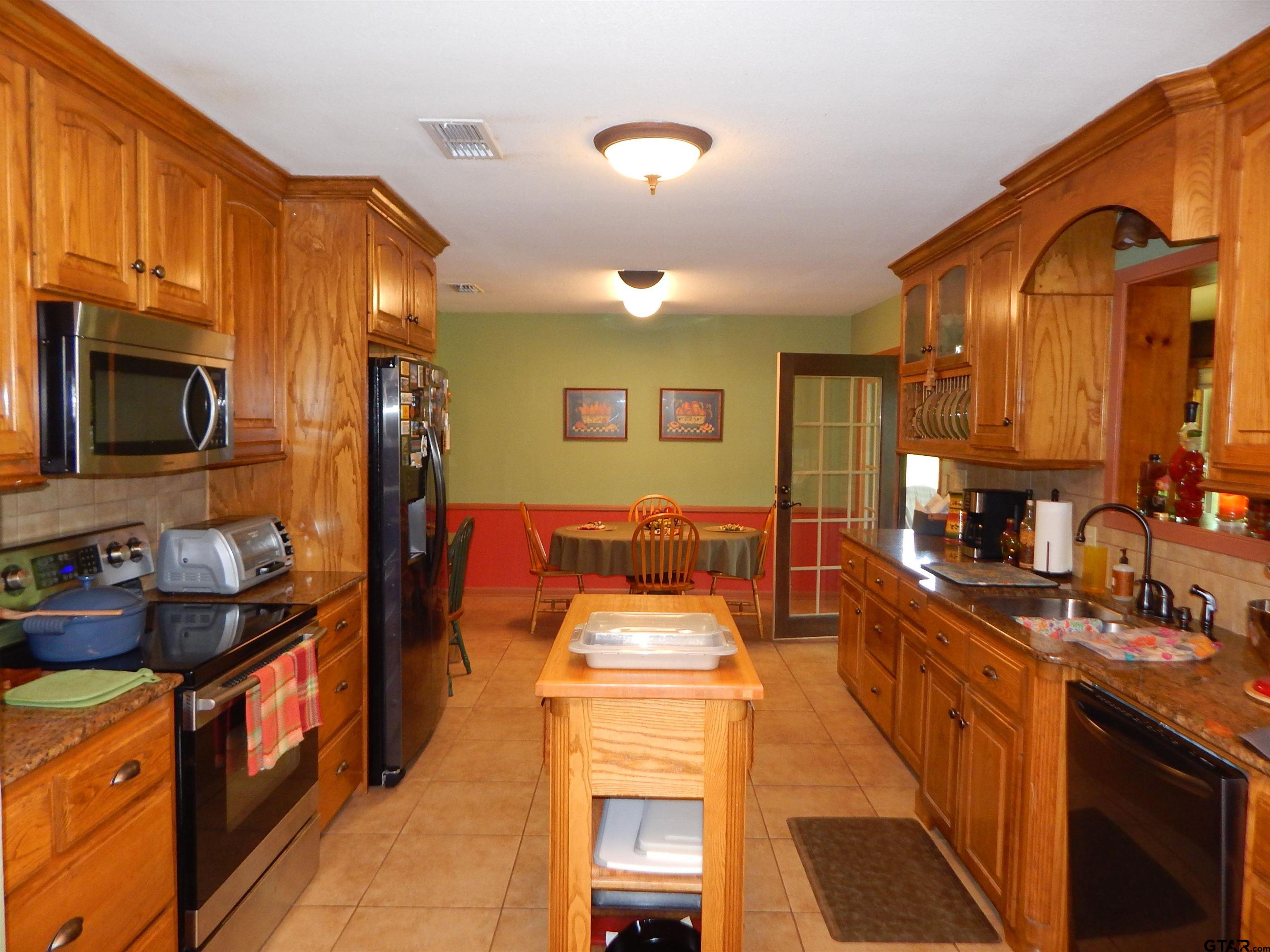 3035 Arrowwood Road Gilmer, TX 75644 - Photo 9 of 32 a kitchen with stainless steel appliances granite countertop a stove a sink and a microwave