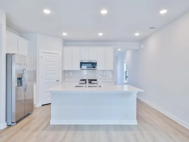 a large kitchen with stainless steel appliances and a refrigerator a oven with wooden floor