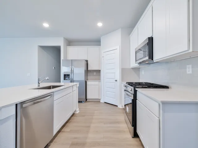a kitchen with stainless steel appliances a sink stove and cabinets