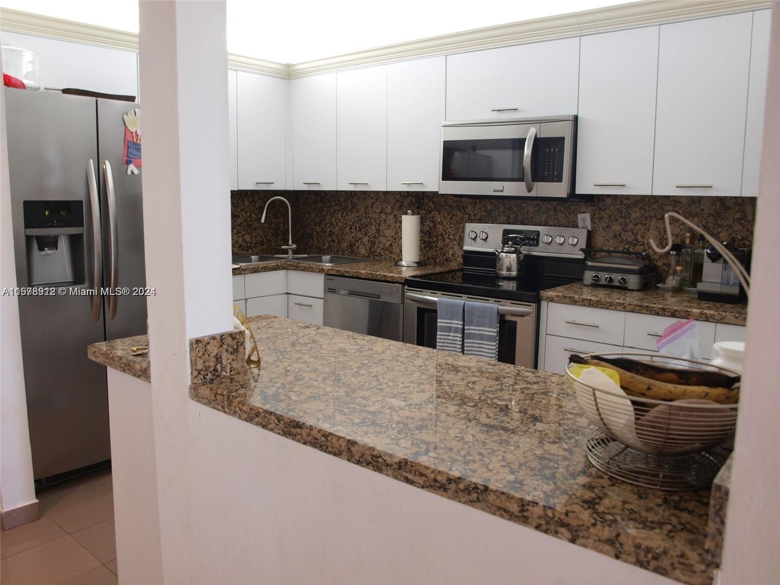 a kitchen with stainless steel appliances granite countertop a stove refrigerator and a microwave
