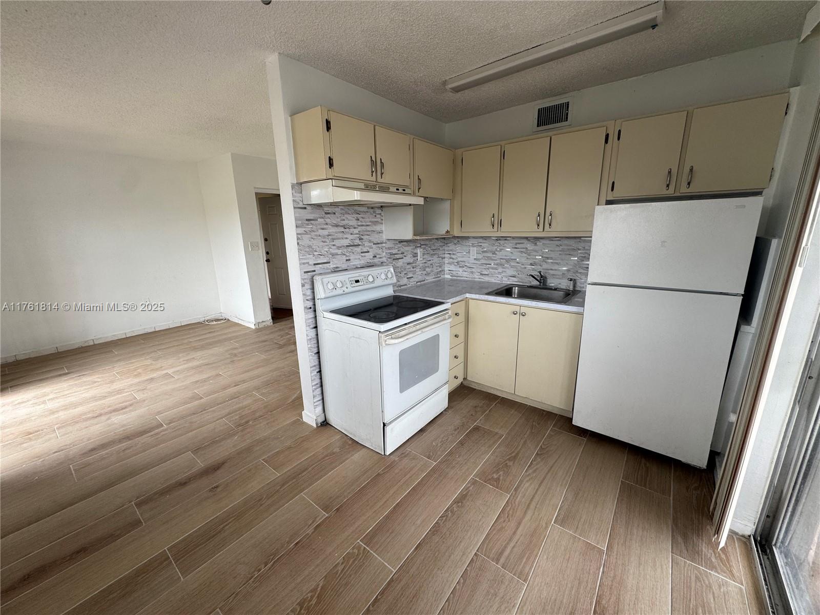 1126 Southwest 3rd Street, Unit 3 Miami, FL 33130 - Photo 2 of 9 a kitchen with a sink a refrigerator a microwave and cabinets