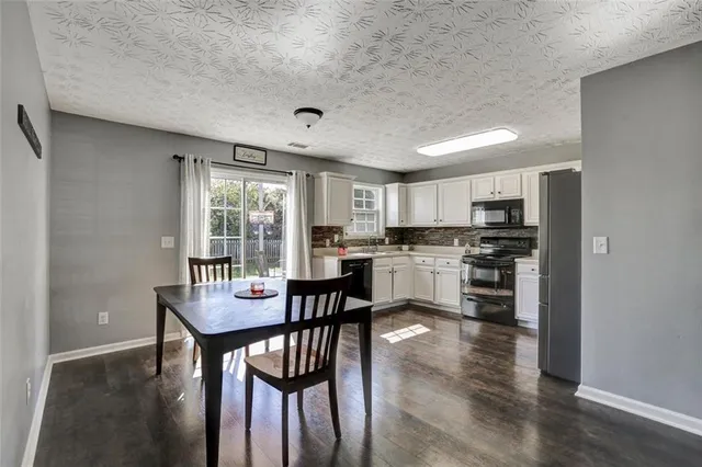 a kitchen with a dining table chairs and refrigerator