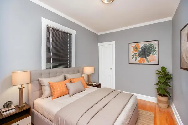 a bedroom with a bed and a lamp on dresser