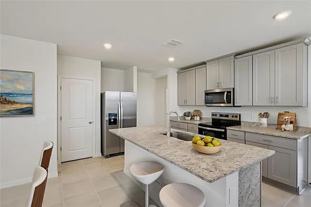 a kitchen with stainless steel appliances granite countertop a sink a stove a refrigerator a stove a dining table and chairs