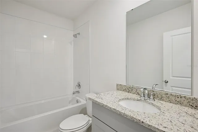 a bathroom with a granite countertop sink toilet tub and shower
