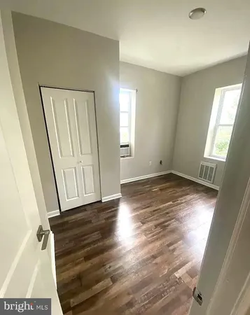 an empty room with wooden floor and window