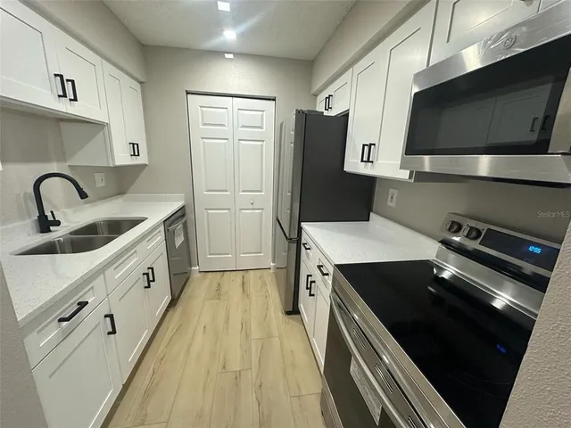 a kitchen with stainless steel appliances a sink dishwasher a refrigerator and a stove