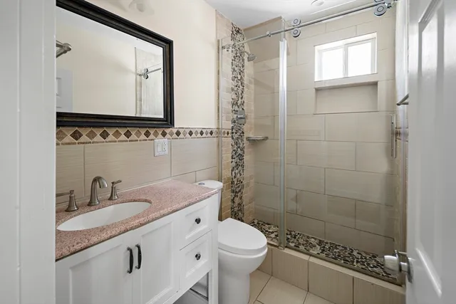 a bathroom with a granite countertop sink a mirror and a shower