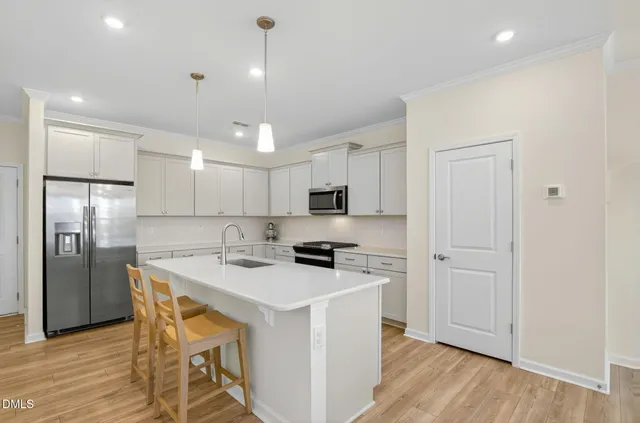 a kitchen with stainless steel appliances kitchen island granite countertop a refrigerator a stove a sink a dining table and chairs with wooden floor