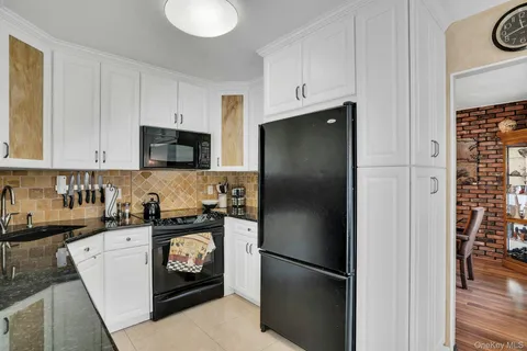 a kitchen with stainless steel appliances granite countertop a refrigerator a stove a sink and a white cabinets