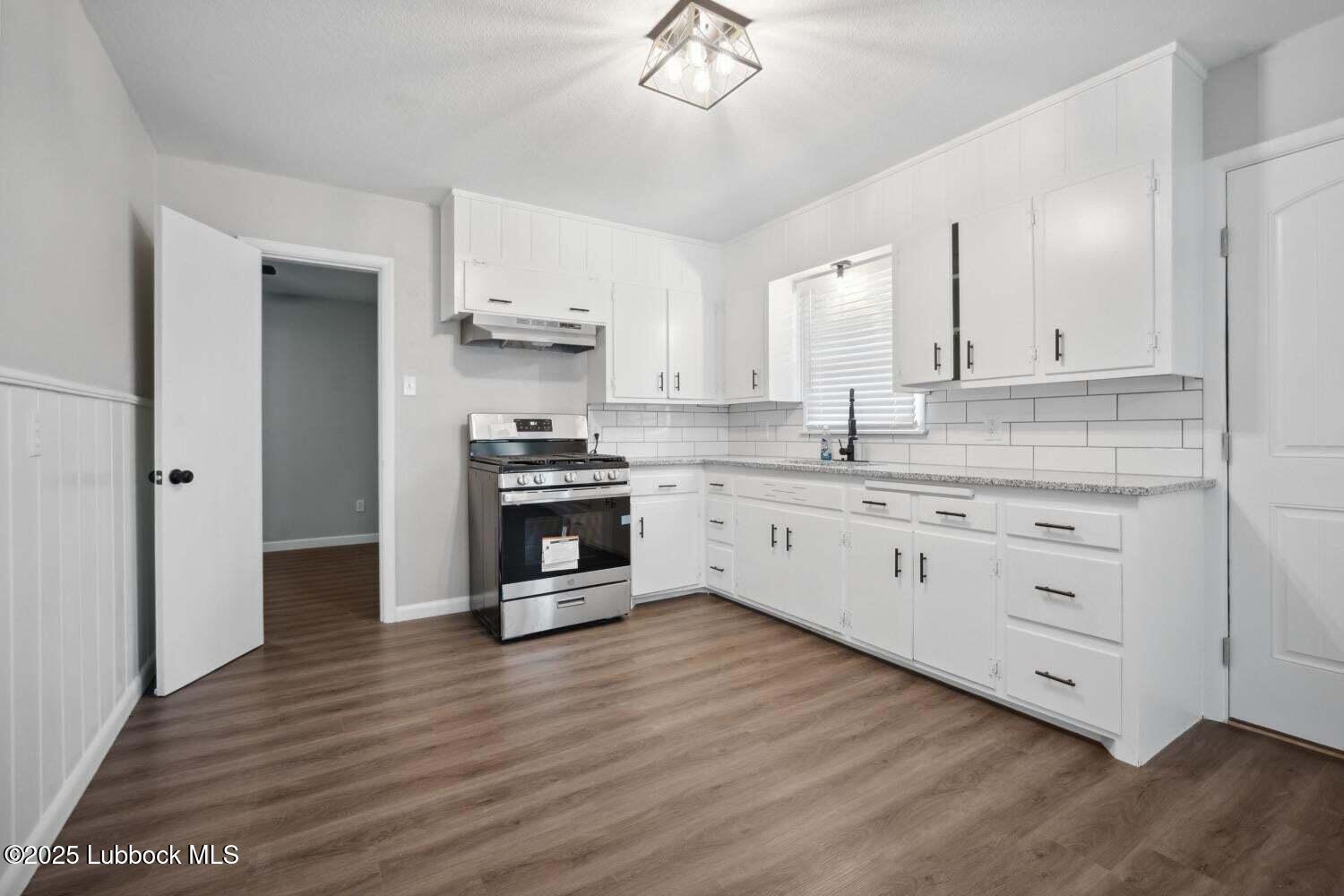 2004 45th Street Lubbock, TX 79412 - Photo 9 of 18 a kitchen with stainless steel appliances a white stove top oven cabinets and a wooden floor