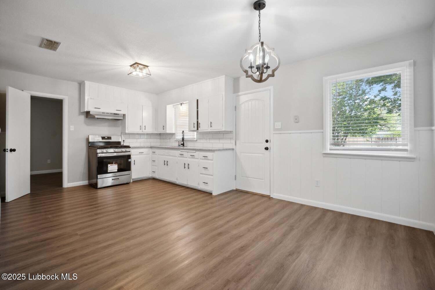 2004 45th Street Lubbock, TX 79412 - Photo 10 of 18 a large kitchen with stainless steel appliances granite countertop a stove a sink dishwasher a refrigerator and a dining table with wooden floor