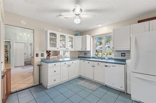 a kitchen with granite countertop white cabinets white appliances with a sink and dishwasher
