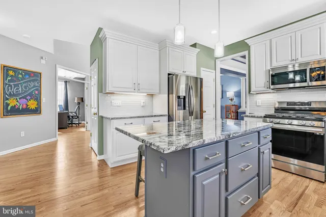 a kitchen with stainless steel appliances granite countertop a refrigerator a stove and a wooden floors