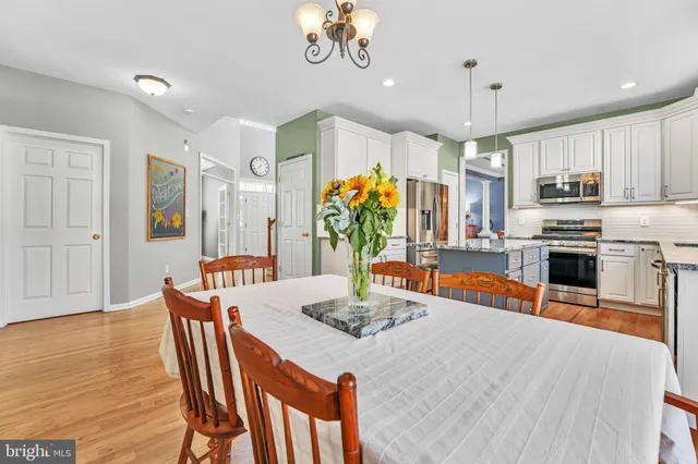 a kitchen with stainless steel appliances kitchen island granite countertop a refrigerator a stove a sink dishwasher and a dining table with wooden floor