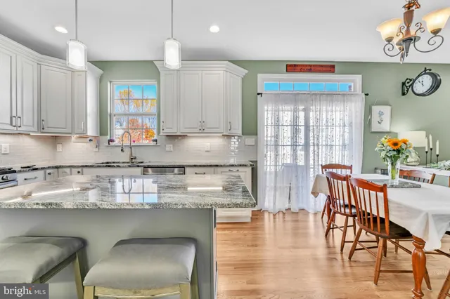 a kitchen with stainless steel appliances granite countertop a stove top oven a dining table and chairs with wooden floor