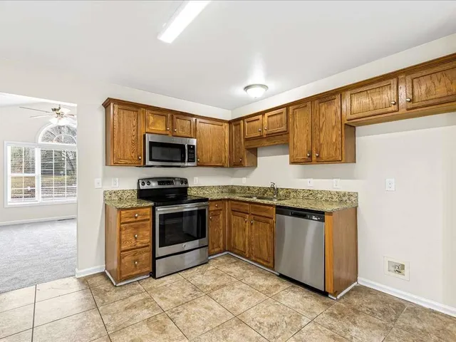 a kitchen with stainless steel appliances granite countertop a stove top oven a sink dishwasher a dining table and chairs with wooden floor