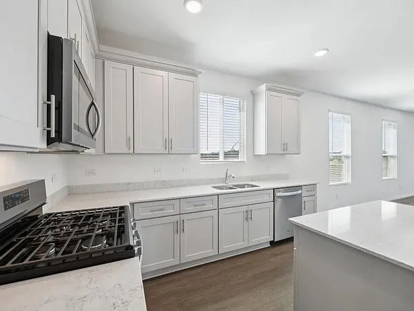 a kitchen with white cabinets sink and stove