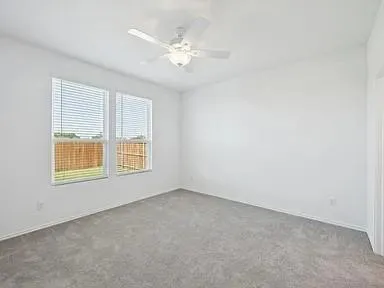 an empty room with a chandelier fan and windows