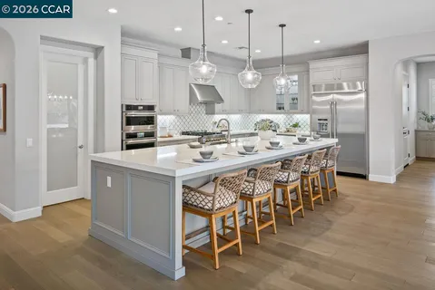 a kitchen with stainless steel appliances kitchen island granite countertop a stove a sink a dining table and chairs