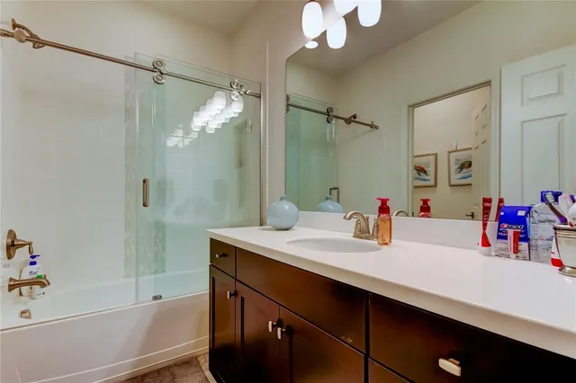 a bathroom with a sink vanity granite tub shower and a mirror