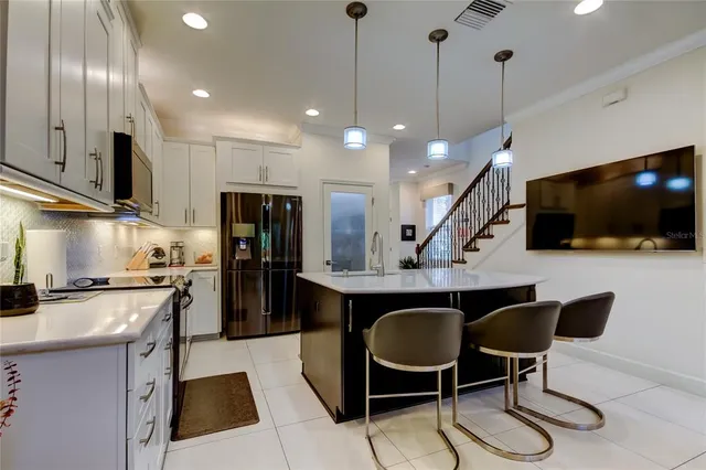 a kitchen with stainless steel appliances a stove a sink a microwave a refrigerator and chairs