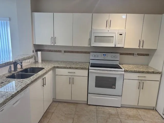 a kitchen with granite countertop white cabinets and white appliances