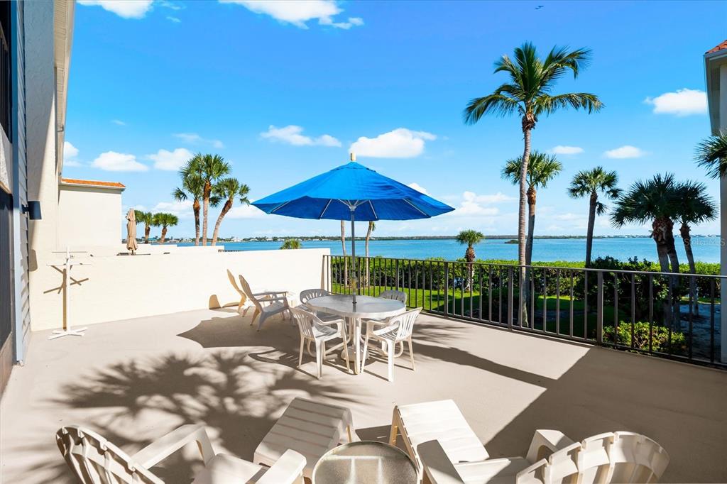 1551 Beach Road, Unit 207 Englewood, FL 34223 - Photo 27 of 40 a view of a patio with a table and chairs under an umbrella with wooden fence