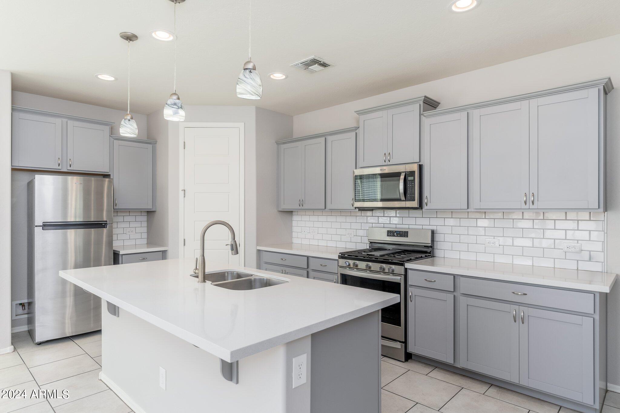 2764 West Apollo Road Phoenix, AZ 85041 - Photo 9 of 45 a kitchen with a sink stainless steel appliances and white cabinets